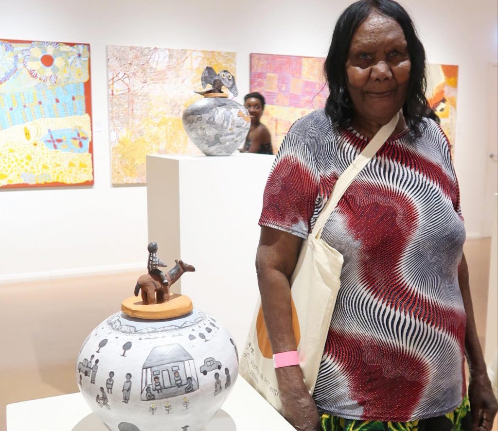 Dawn Ngala Wheeler with her work at Desert Mob 2020 - Courtesy Hermannsburg Potters
