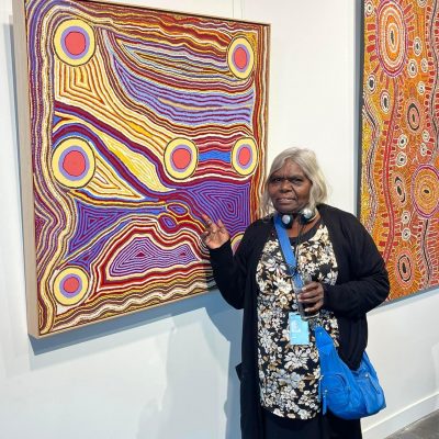 Artist Anawari Inpiti Mitchell with a painting by her sister Angilyiya Mitchell 